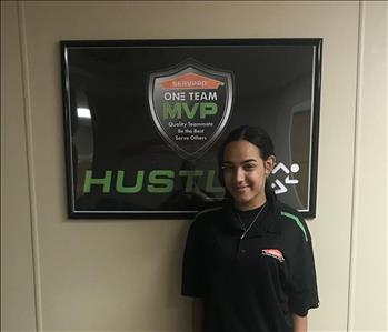 Haydee standing in front of a SERVPRO plaque in our office hallway