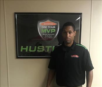 Eric standing in front of a SERVPRO plaque in our office hallway.