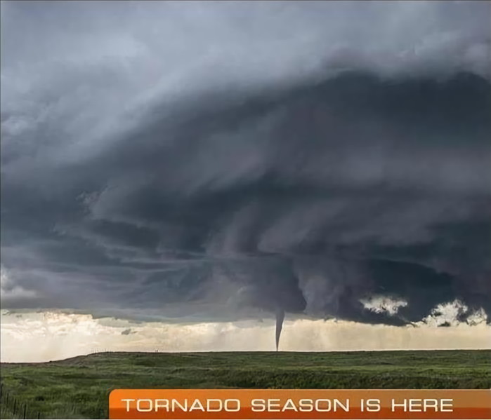 Tornado funnel touches down in a large field.